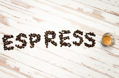 The word espresso written with coffee beans and a fresh real espressoの写真素材