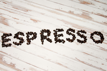 The word espresso written with coffee beans on a white wooden tableの写真素材