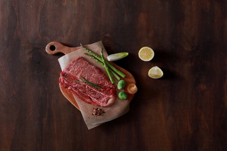 raw beef steak with asparagus and lemons on wooden background