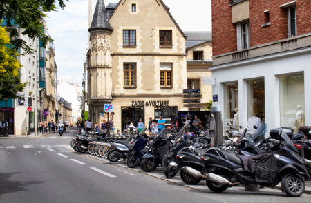 PARIS - JULY, 2016: View of motorcycles parked on one of the streets in Le Marais district. Fashion stores and traditional French architecture style buildings are in the view.のeditorial素材