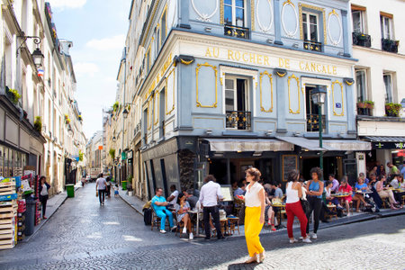 PARIS - JULY, 2016: French woman passes by a cafe/bistro where people have lunch on Rue Montorgueil street in Paris. The image shows city's lifestyle.のeditorial素材