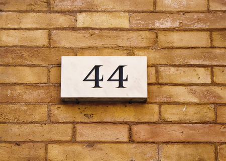Engraved building number of fourty four on old, brown brick wall in Rome.の写真素材
