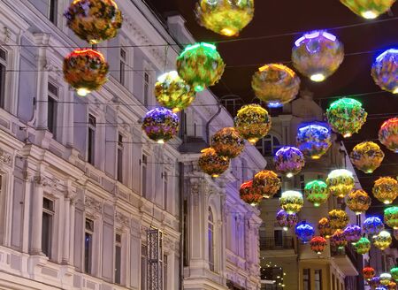 View of street decorations with colourful lights made with flowers in city center of Moscow for Christmas and New Year Eve. Historical, old Russian building in the background. Blurry motion imageの写真素材