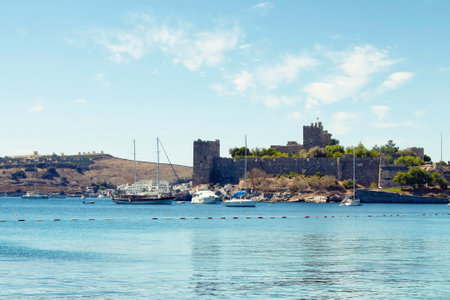 Luxury yachts (sailing boats) parked on turquoise water in front of Bodrum castle. The image shows...