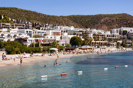 People swim at Icmeler beach near Bodrum city center. It is a sunny summer day. Traditional, white, typical summer houses reflect region's architectural style.のeditorial素材