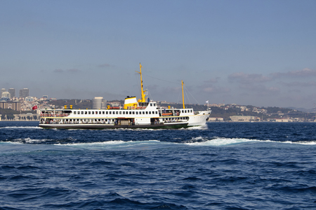Traditional public ferry crosses Bosphorus from European to Asian side. It's a sunny summer day in Istanbul. Besiktas area is in the view in the background.の写真素材
