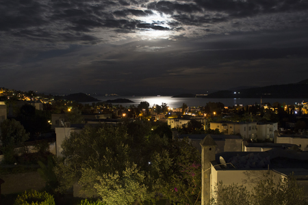 Long exposure of full moon in 2016 summer behind clouds over Aegean sea at Turkbuku village in Bodrum peninsula. Light shines on sea surface.の写真素材