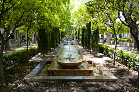 View of water fountain and trees at Hort del Rei park next to Royal Palace of La Almudaina and Catedral de Mallorcaのeditorial素材