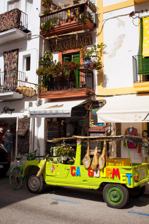 View of a car decorated colorfully and vibrantly and traditional building in the background in Ibiza.のeditorial素材