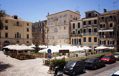 View of cafes, cars and old, historical buildings in Corfu (Kerkyra) island of Greece. It's a sunny summer day.のeditorial素材