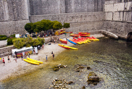 View of people, red/yellow water kayaks at the bottom of walls of Dubrovnik old town. It is a city in southern Croatia fronting the Adriatic Sea.のeditorial素材