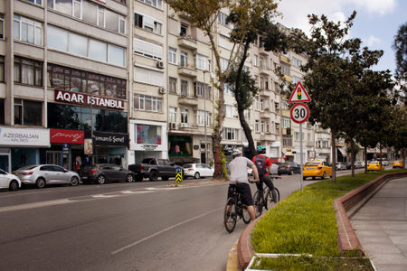 View of two bicycles riders and buildings in the background in Nisantasi / Istanbul that is a popular shopping and residential district.のeditorial素材
