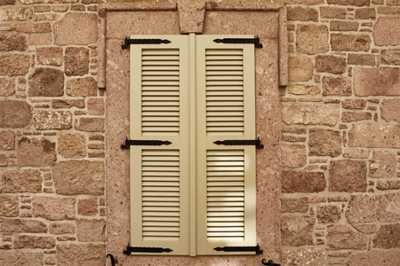 Close up view of closed window with wooden shutters and old, stone wall.の写真素材