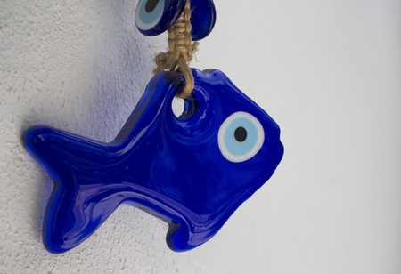 Close up view of an evil eye in shape of fish with white background.の写真素材