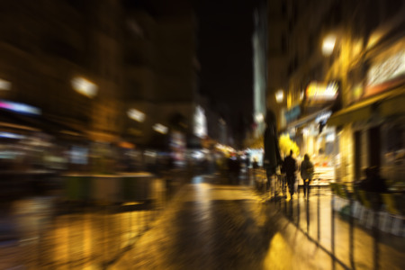 Blurry motion image of people walking on street at night in Paris.の写真素材
