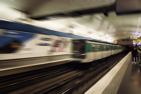 Blurry motion image of train approaching a station in subway station in Paris.