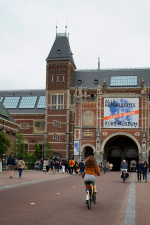 View of people walking and riding bicycles in front of Rijksmuseum. It is a Dutch museum dedicated to arts and history, located at the Museum Square in the borough Amsterdam South.のeditorial素材