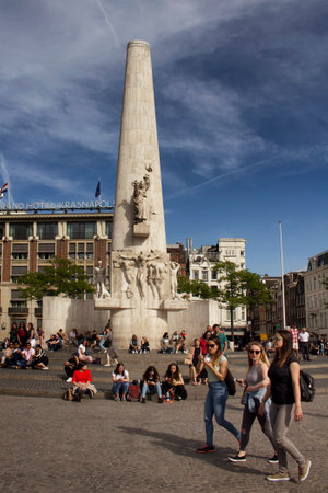 View of people hanging out in front of National Monument in Amsterdam. It is a sunny summer day with blue sky.のeditorial素材