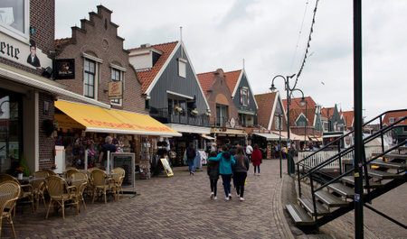 View of people walking at the pier, shops and restaurants in Volendam. It is a Dutch town, northeast of Amsterdam. Itâs known for its colorful wooden houses and the old fishing boats.のeditorial素材