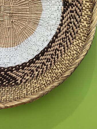 Close up view of wicker bowl knitted in different styles on green background