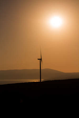 View of wind turbine, Aegean sea and landscpae at sunset captured in Sigacik / Seferihisar district of Izmir / Turkey. Wind power turbines for clean, renewable energy. Sustainability concept.の写真素材