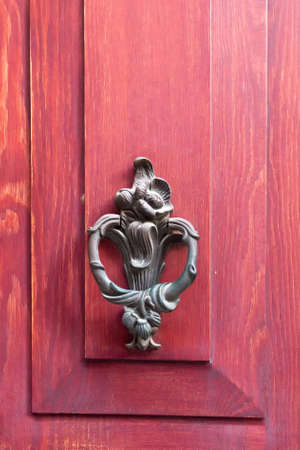 Close up view of old, traditional, ornamental door knob on red wood background.の写真素材