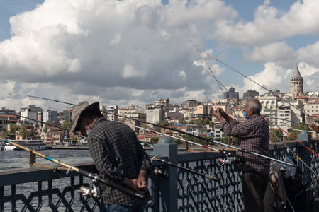 View of fishermen on Galata bridge in Istanbul. Galata tower and Beyoglu district are in background. The image reflects lifestyle and culture of local people. It is a sunny summer day.のeditorial素材