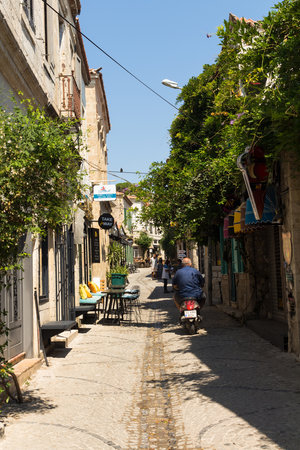 View of people walking on street and old, historical, traditional stone houses in famous, touristic Aegean town called Alacati. It is a village of Cesme, Turkey. It is a sunny summer dayのeditorial素材