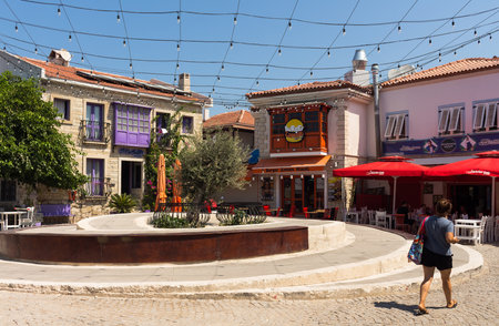 View of woman walking on street and old, historical, traditional stone houses in famous, touristic Aegean town called Alacati. It is a village of Cesme, Turkey. It is a sunny summer dayのeditorial素材