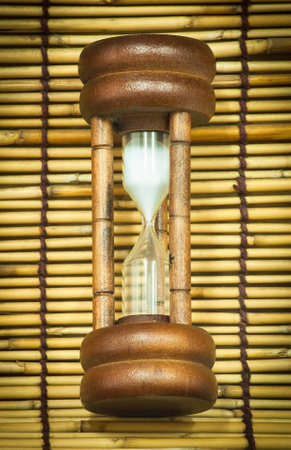 Hourglass laying on bamboo woven together.