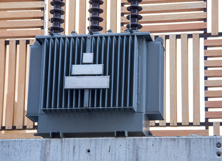 Electricity distribution transformer with cooling ribs on wood wall