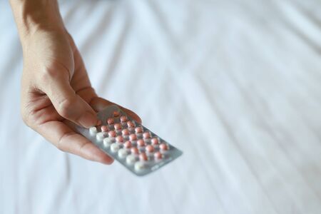 Women carrying birth control pills in bedの写真素材