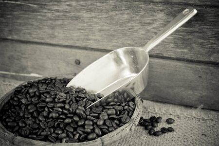Coffee beans and silver scoop on old wood background with retro black and white filter effectの写真素材