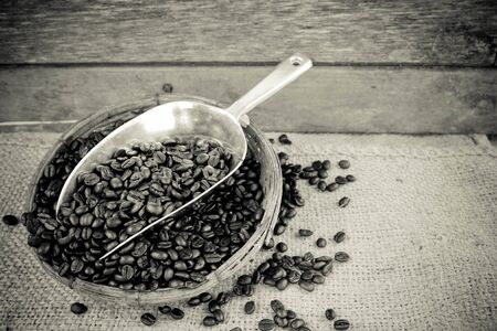 Coffee beans and silver scoop on old wood background with retro black and white filter effectの写真素材