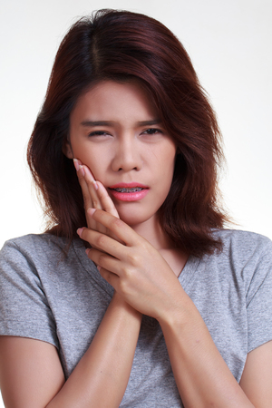 Teen woman pressing her bruised cheek with a painful expression as if she's having a terrible tooth ache.の写真素材