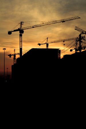 Silhouette of construction workers on scaffold working under a hot sunの写真素材