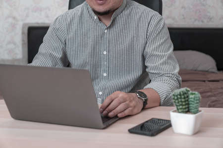 Young businessman working on laptop in home, rear view green screen of business man hands busy using laptop at office desk, typing on computer sitting at wooden tableの写真素材