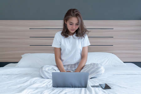 Top View of Beautiful Young Woman Sleeping Cozily on a Bed in His Bedroom at Night. she is playing phone until sleepの写真素材