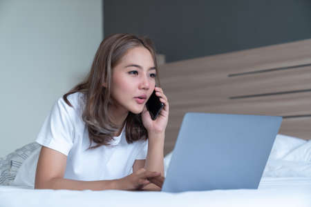 Top View of Beautiful Young Woman Sleeping Cozily on a Bed in His Bedroom at Night. she is playing phone until sleepの写真素材