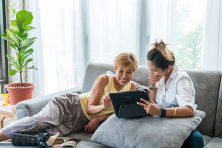Young businessman in eyewear  working at home with laptop and phone on desk. Pleasant happy man communicating in social network, searching information online.の写真素材