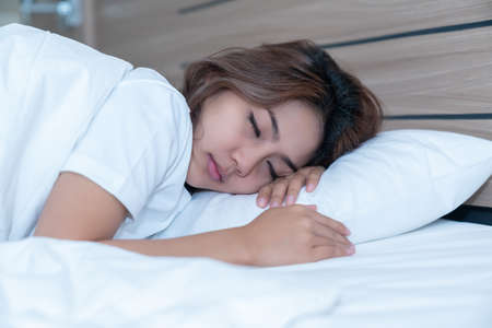Beautiful Asian woman lying down and smiling the bed and her laptop. WFH Working from home in quarantine lockdown. Social distancing Self Isolationの写真素材