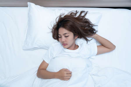 Beautiful Asian woman lying down and smiling the bed and her laptop. WFH Working from home in quarantine lockdown. Social distancing Self Isolationの写真素材