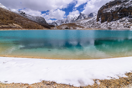 The green milk Lake is surrounded by snow on the mountains in Yading Nature Reserve, China.の写真素材