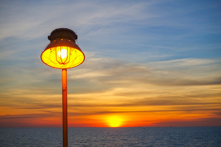 Lighting of warm lamp and lighting of sunset at sea with beautiful sky and clouds in the evening with twilight time on offshore platform.の写真素材