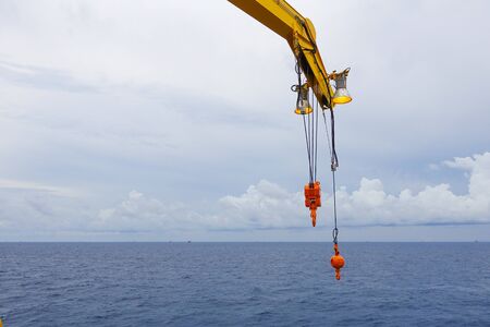 Crane boom and crane lighting in the sea with sky and clouds background on offshore platform.の写真素材