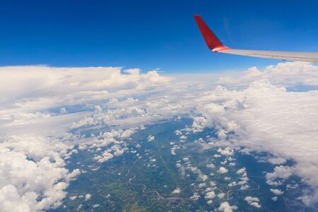 View from airplane window. Wing of an airplane flying above the clouds and town over Thailand.の写真素材