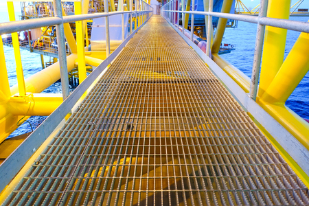 Bridge and handrail with grating on offshore platform with lighting in evening.の写真素材