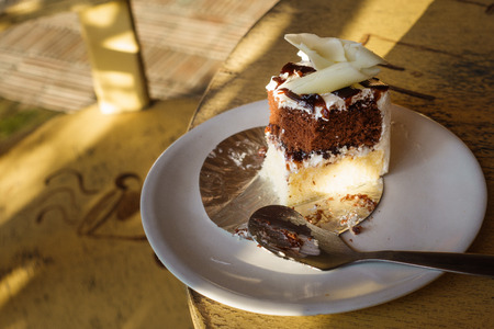 slice of coffee cake on dish on the wooden table with sun light.の写真素材