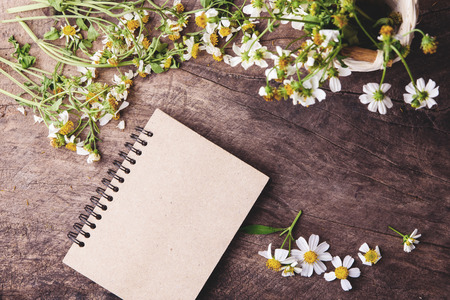 Blank notebook with white flower and bas ket of flower on vintage wooden table View from above with copy spaceの写真素材