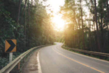 Blur of  road is surrounded by pine trees forest to the flare light of the sun, vintage tone